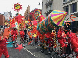Festival on the streets, group of cyclists moving with a float in the shape of a rocket.